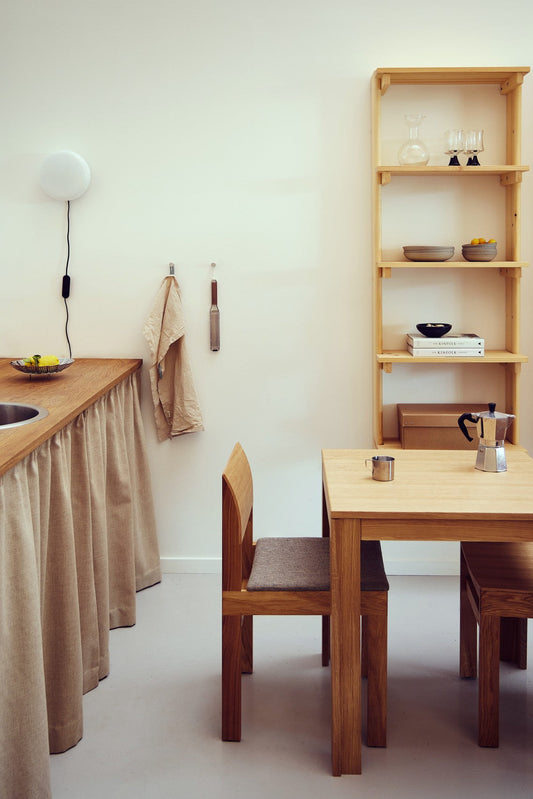 Køkken med spisebord og træreol med hylder