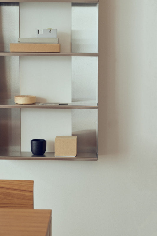 Kontor med en rektangulær pyntehylde i metal på væggen.